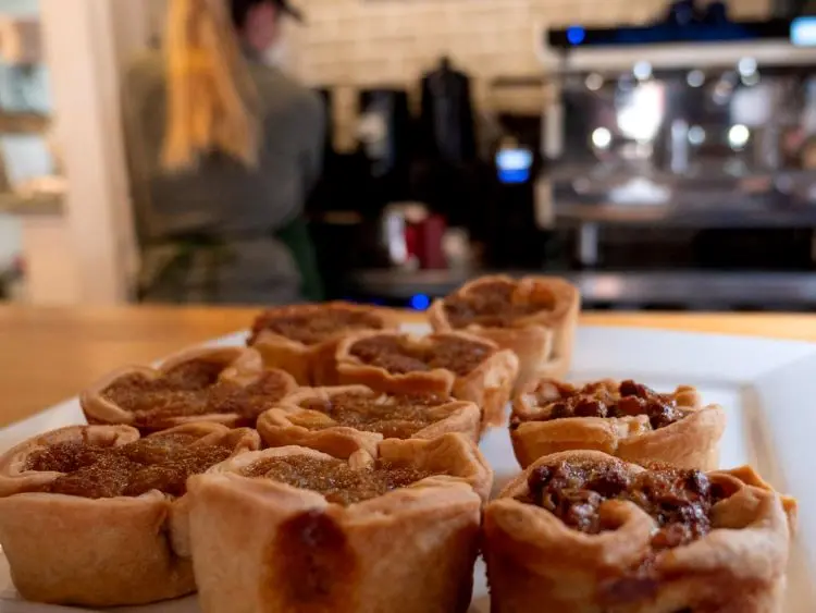 Close-up of several perfectly baked butter tarts with gooey fillings.