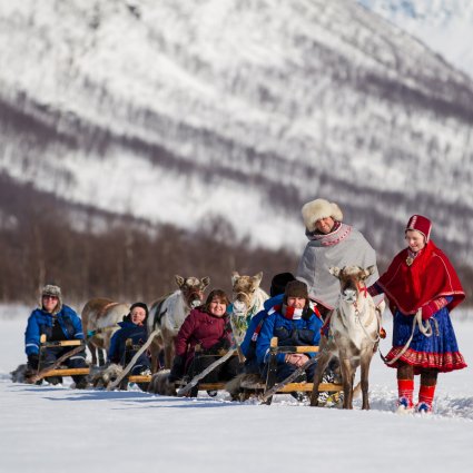 Travelers gathered inside a warmly lit Lavvu, listening to a Sami storyteller