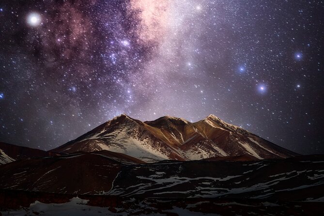 The Milky Way arches over a dark landscape, the lodge lights glowing softly in the foreground