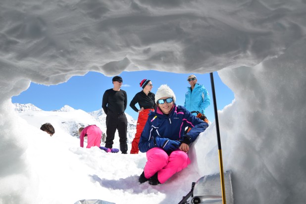 A wide shot of someone ice climbing against a backdrop of snow-capped mountains