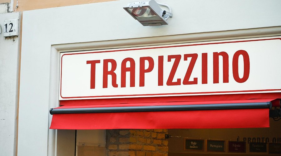 A Trapizzino, filled with Pollo alla Cacciatora, ready to be bitten into, the filling practically overflowing.