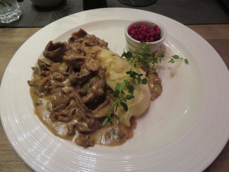 Action shot of someone kicksledding on a winding trail through a snow-laden forest, captured at eye level to convey the feeling of movement.