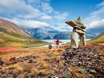 An Indigenous guide from Mahikan Trails pointing out animal tracks in the snow during a wildlife tracking excursion in Spray Valley, emphasizing the cultural significance of tracking and the ecological knowledge shared by the guides.
