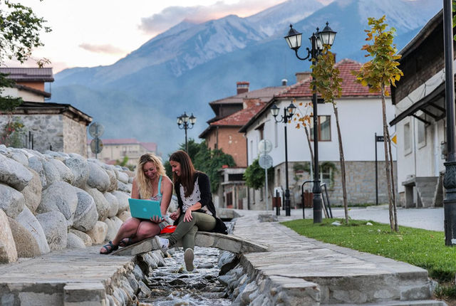 A digital nomad working on a laptop with a view of the mountains in Bansko, Bulgaria