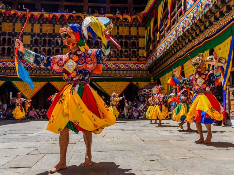 Monks adorned in elaborate silk brocade robes during the Paro Tshechu festival