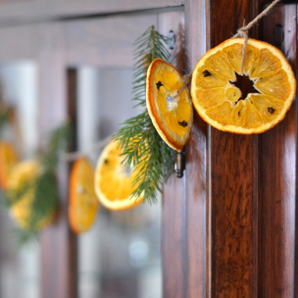 A wider shot of the rustic kitchen, showcasing the dried orange garlands adorning various surfaces and creating a warm, inviting atmosphere.