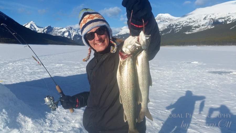 Fat biker on a snowy trail near Cascade Ponds in Banff, reflecting the mountain in the water.