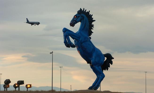 A side view of the Blue Mustang at sunset, highlighting the silhouette against the colorful sky.