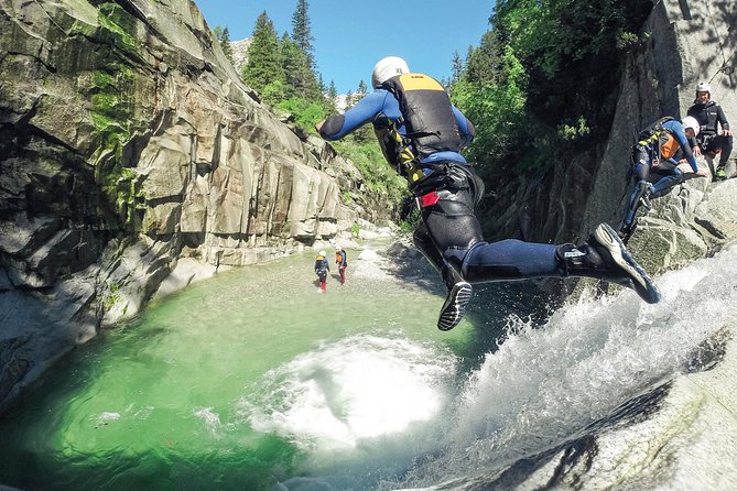 A low-angle shot of a canyoneer rappelling down a frozen waterfall, showcasing the height and the ice formations and emphasizing the cold and stark landscape.