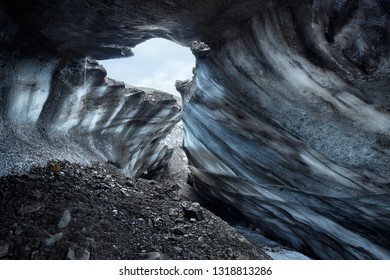 A group of explorers inside an ice cave, highlighting the otherworldly beauty of the blue ice formations and the sense of discovery.