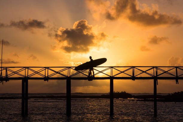 A surfer silhouetted against a stunning sunset over the ocean. This image showcases the serene beauty and adventurous spirit of surfing in Siargao.