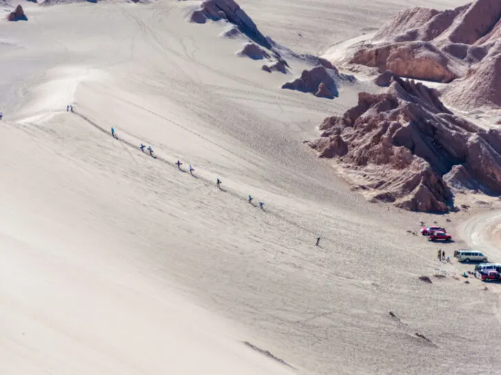 A person sandboarding down a steep sand dune in Death Valley, Atacama Desert, Chile, illustrating the adrenaline rush and adventure of the activity.