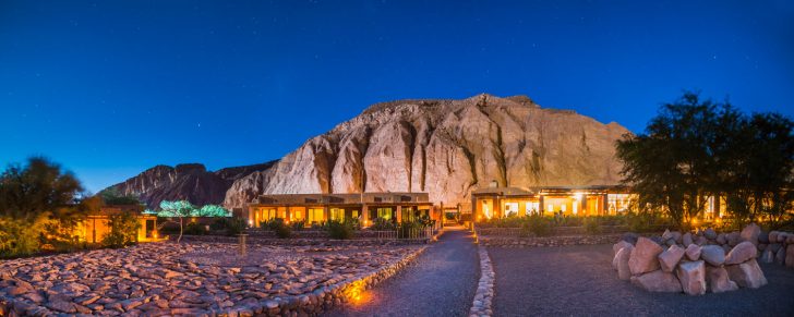 Alto Atacama Desert Lodge exterior blending into the desert landscape, showcasing its adobe architecture and natural materials, highlighting the lodge's commitment to minimizing light pollution for optimal stargazing.