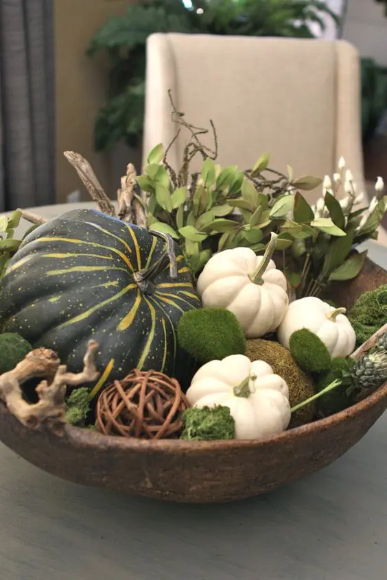 A cozy farmhouse living room is decorated for fall with pumpkins, blankets, and warm lighting, creating an inviting atmosphere for relaxation and comfort.