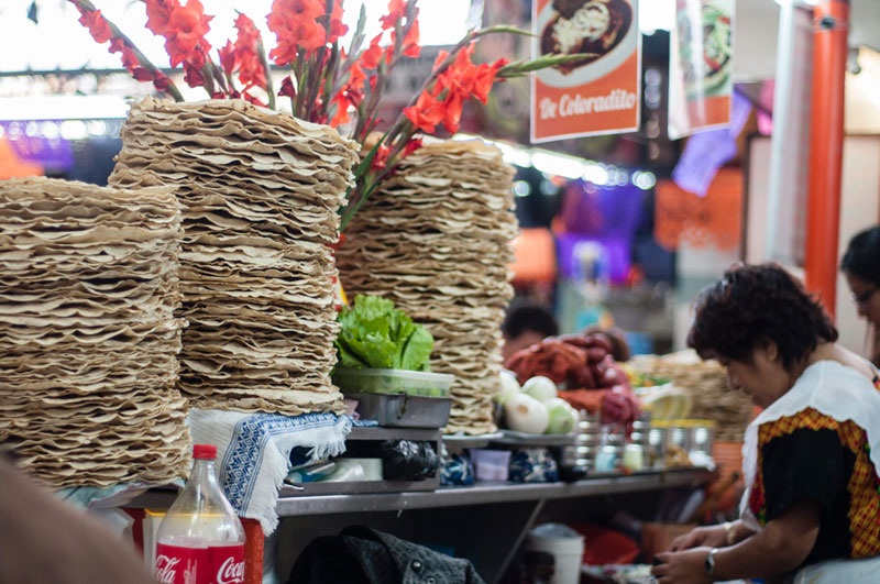 A close-up of a tlayuda overflowing with beans, cheese, avocado, and salsa, capturing the vibrant colors and textures of the toppings.
