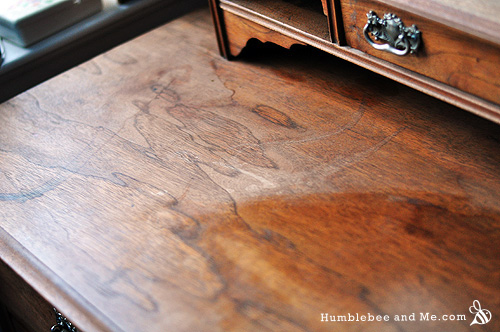 Warmly lit homestead living room during winter. A beeswax wood polish is being applied to a solid wood coffee table using a soft cloth.