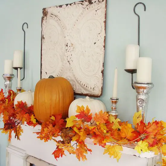 A living room decorated for fall with natural elements like pumpkins, wooden accents, and knitted throws, showcasing a cozy and sustainable approach to home decor.