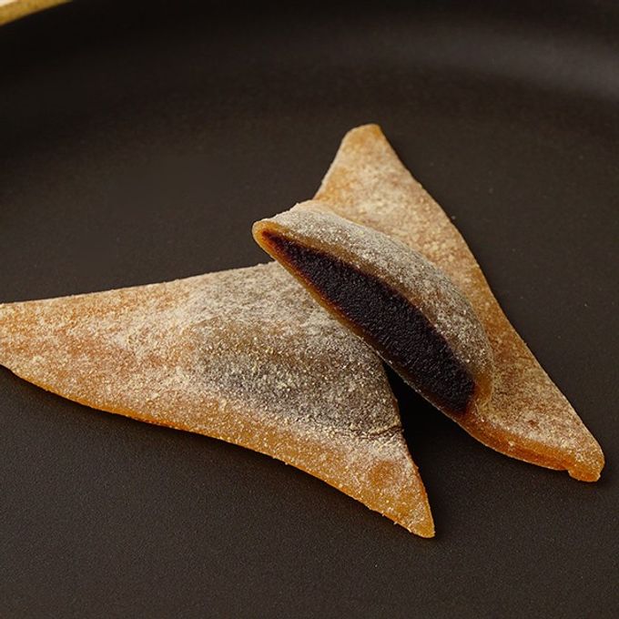 Close-up shot of Yatsuhashi cookies arranged artfully on a plate. The image captures the unique shape and texture of the cookies, showcasing the variety of flavors available.