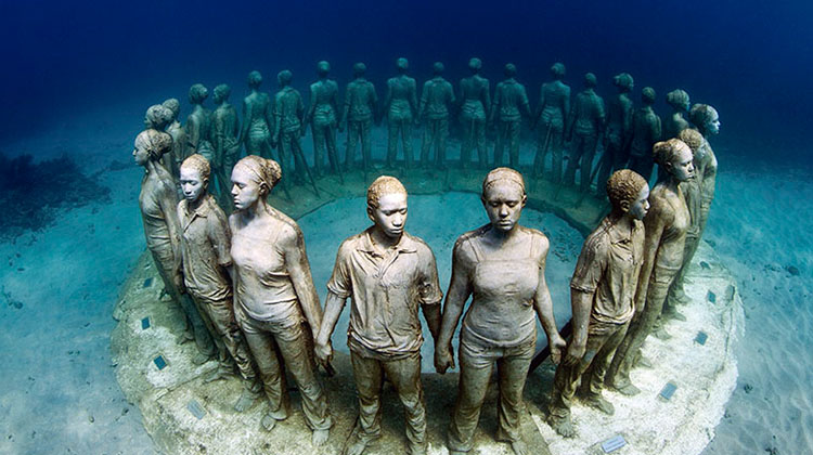 People underwater with sculptures
