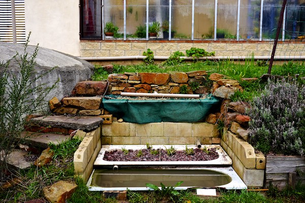 DIY greywater recycling system made from repurposed barrels and pipes.