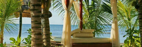 A couple kayaking together in the calm waters of Bai Dam Trau, with lush green hills of Con Dao National Park visible in the background.