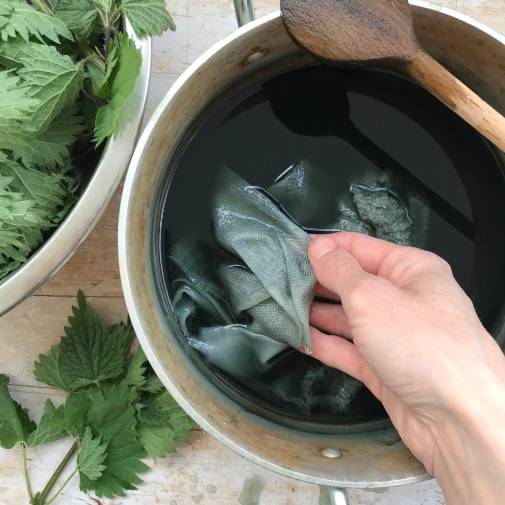 Hands carefully placing fabric simmering dye pot