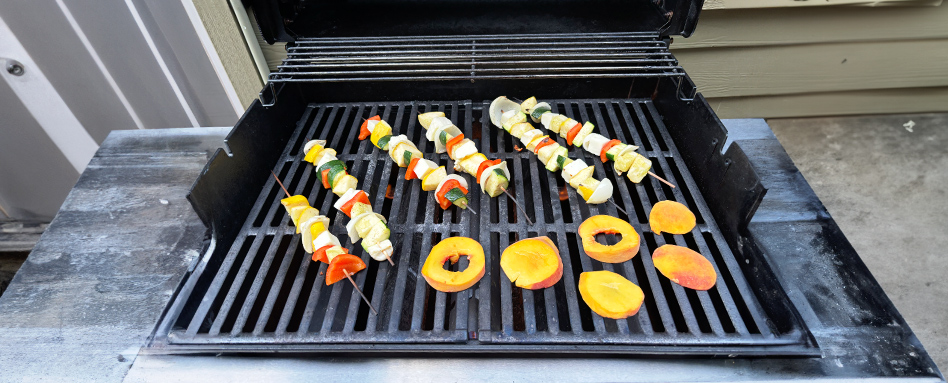A close-up shot of a hand picking up small pieces of colorful plastic from a sandy beach, with the ocean visible in the background.
