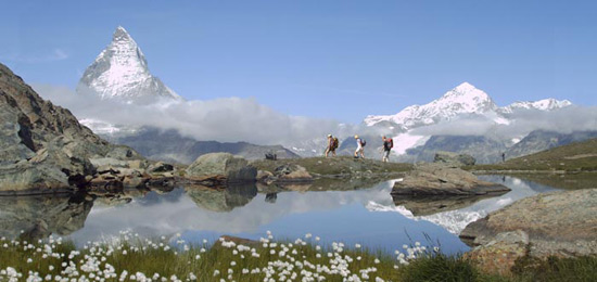 Hikers traversing a snow-covered pass on the Haute Route, with the Matterhorn in the background, showcasing the beauty and challenge of the trek.