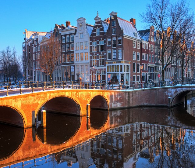 The charming Pulitzer Amsterdam, comprised of interlinked canal houses, reflected in the canal.