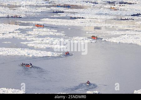 Action shot of a group of people ice canoeing on the St. Lawrence, with the Quebec City skyline in the background, taken with a wide-angle lens to emphasize the scale of the river. Use a fast shutter speed to freeze the action