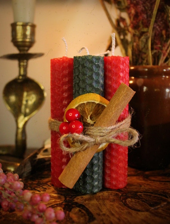 A photo showcasing the elements of the Yule centerpiece on a linen background, including a beeswax candle and wreath.