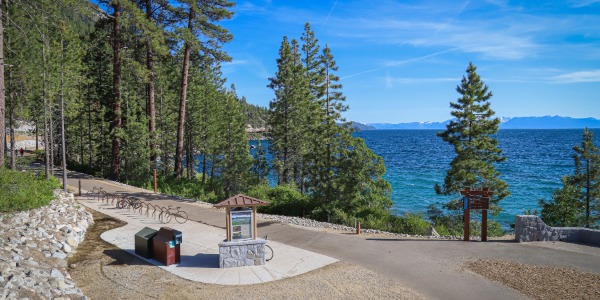 Elena and Mateo hiking on the East Shore Trail, showcasing the scenic views of Lake Tahoe and the surrounding landscape, with wildflowers visible in the foreground.