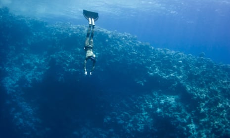Freedivers ascending from the depths of the Blue Hole, showcasing the vibrant blue water and dramatic coastline in Dahab, Egypt.