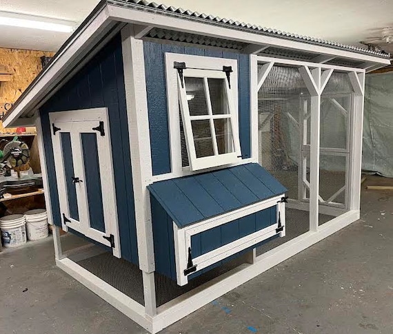 A completed chicken coop in a backyard with chickens roaming freely