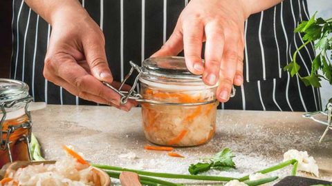 Mason jar fermenting pickles and cabbage with bubbles