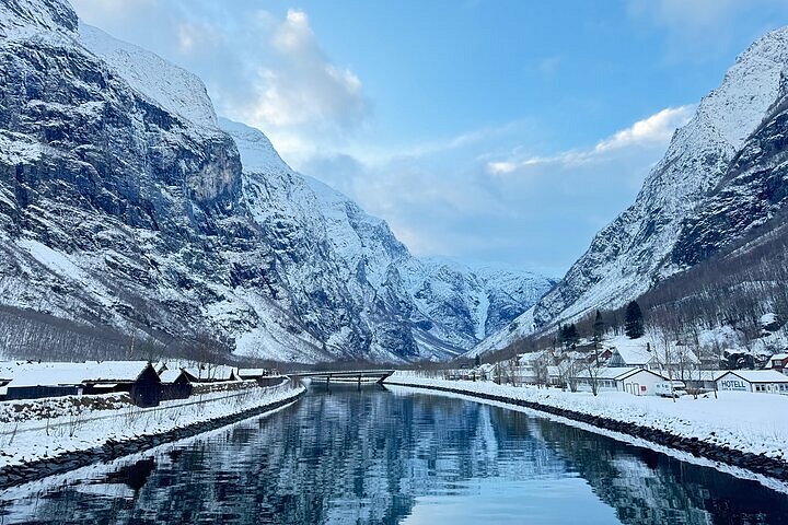 Kayaks gliding through a fjord surrounded by snow-capped mountains.