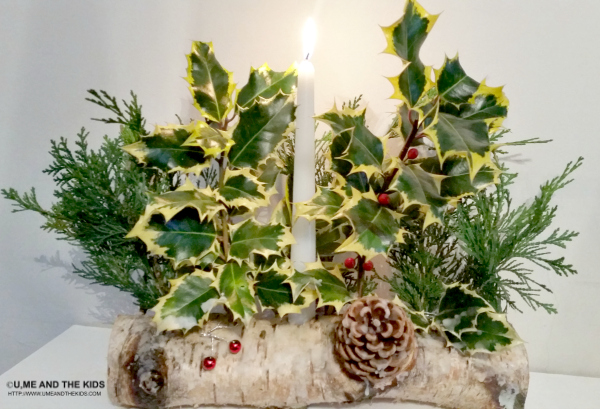 Hands attaching evergreen branches to a log