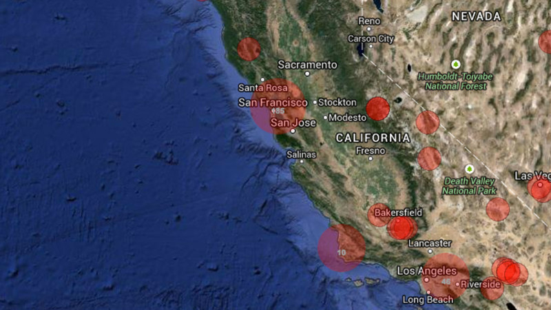 Waves gently washing over the colorful glass pebbles on Glass Beach, filmed with bright, golden hour lighting