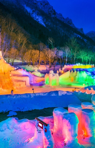 A close-up of ice formations in Sounkyo Gorge, with icicles glittering like diamonds and a snow-covered landscape visible in the background, emphasizing the beauty and detail of the frozen waterfalls.