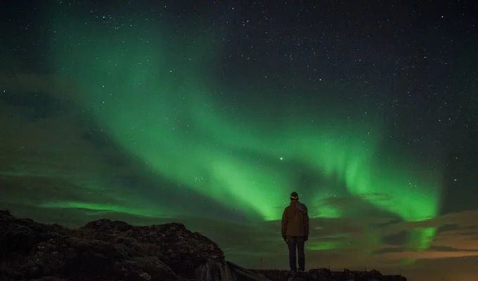 The Aurora Borealis dancing across the Icelandic sky, with mountains and glaciers in the foreground, capturing the awe and wonder of this natural phenomenon.
