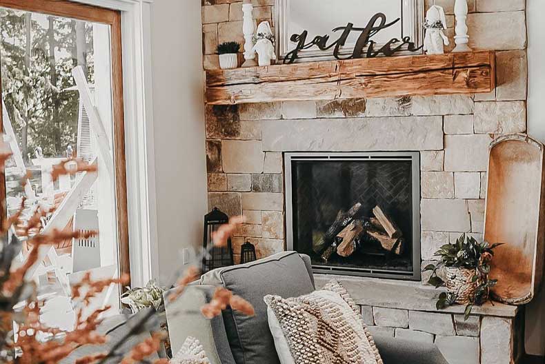 A farmhouse fireplace mantel with pumpkins and fall foliage