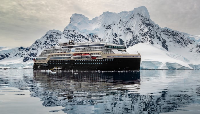 A diver swims with manta rays during a night dive in Kona, Hawaii. The mantas are illuminated by dive lights.