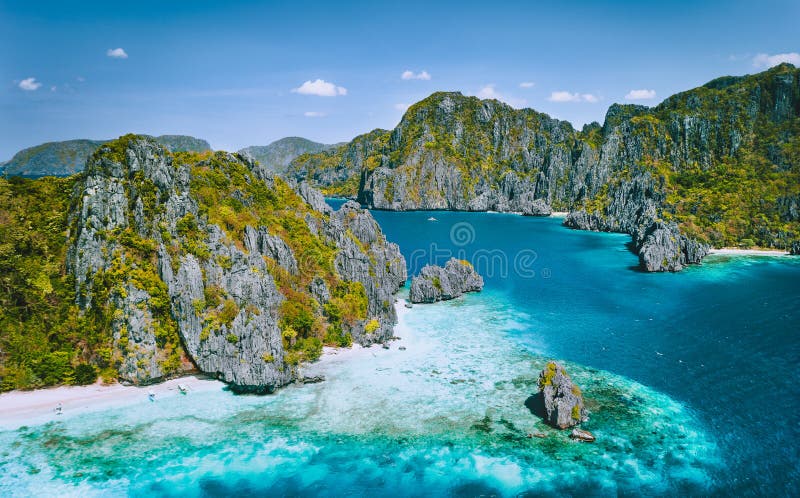 Dramatic limestone cliffs rise from the emerald green sea in Palawan, Philippines.