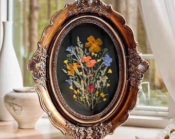 Pressed flowers and herbs displayed in a grouping on a wall.