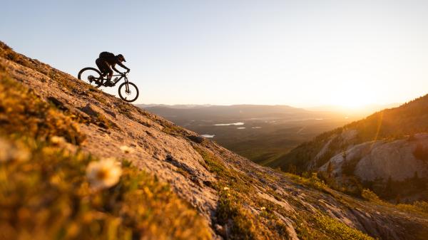 Fat biker riding on a snow-covered trail in a mountainous area. The picture highlights the remoteness and beauty of the winter landscape and serves as a visual representation of resilience and adventure in extreme conditions.