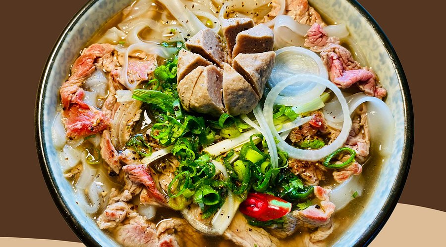 A bowl of Pho Bo, showcasing the rich broth, tender beef slices, and fresh herbs.