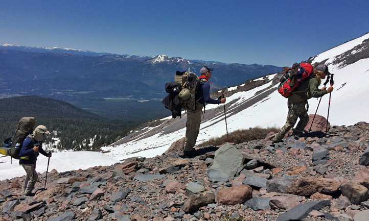 A wide-angle shot of Aconcagua at golden hour, showcasing its immense scale and the surrounding vast landscape. The photo is color graded to enhance the red hues of the rocks, with a shallow depth of field.
