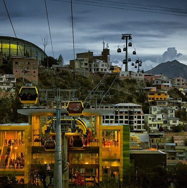A small wooden cabin in the wilderness with mountains in the background.