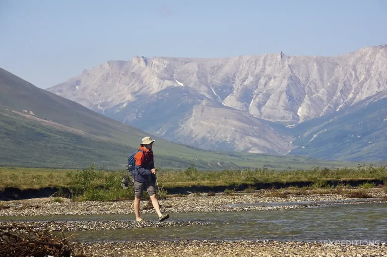 Packrafters navigating a river in a remote Alaskan landscape, alt text: Two packrafters paddle down the Noatak River, surrounded by the vast, treeless Arctic tundra of the Brooks Range in Alaska.