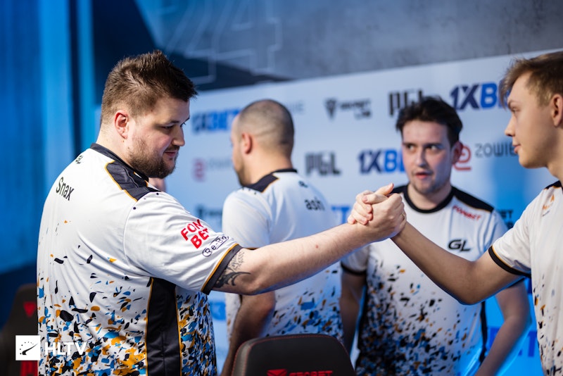 A close-up shot of a Counter-Strike 2 player's hands intensely gripping the mouse and keyboard during a match, capturing the high-stakes environment and the player's focus.